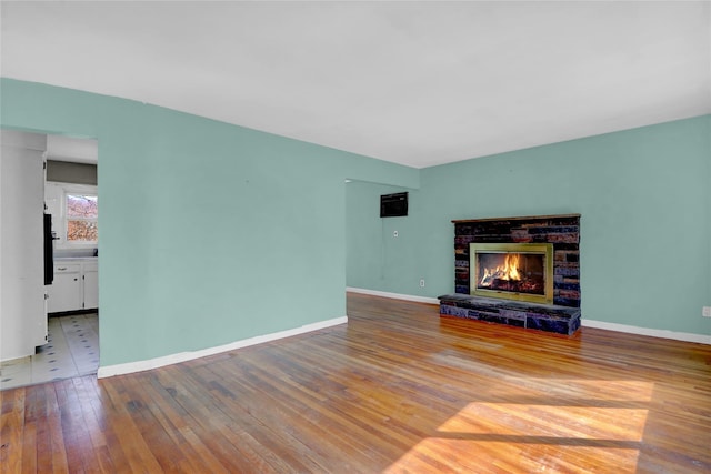 unfurnished living room featuring a fireplace, baseboards, and hardwood / wood-style flooring