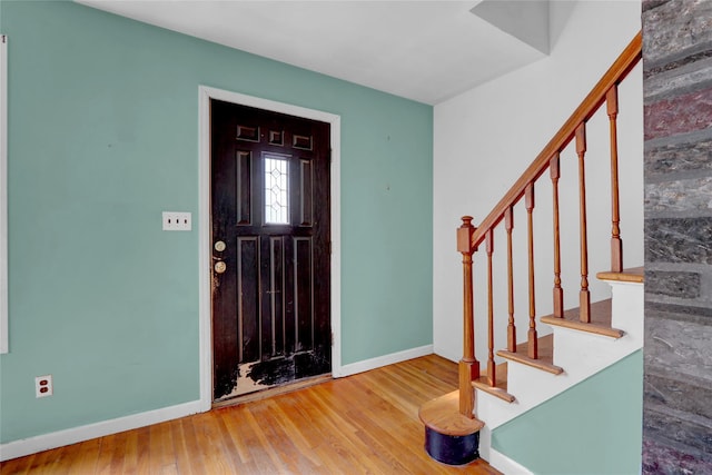 entryway with stairs, baseboards, and wood finished floors