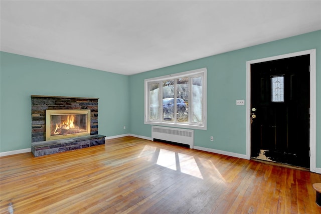 unfurnished living room featuring baseboards, a fireplace, radiator heating unit, and hardwood / wood-style flooring