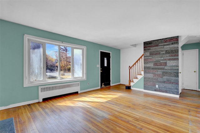 foyer with stairs, radiator heating unit, baseboards, and wood-type flooring