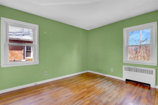 spare room with baseboards, radiator, and a healthy amount of sunlight