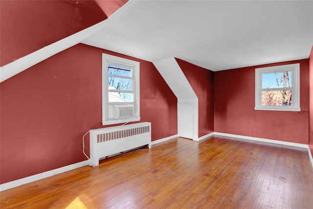 bonus room with hardwood / wood-style flooring, radiator heating unit, baseboards, and vaulted ceiling