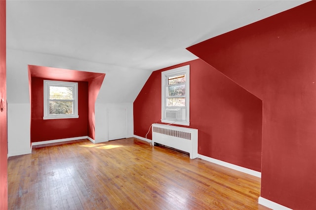 bonus room with hardwood / wood-style floors, vaulted ceiling, radiator, and baseboards