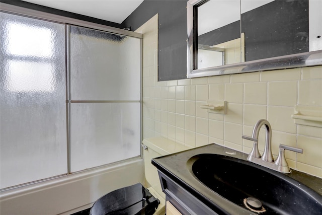 bathroom featuring combined bath / shower with glass door, backsplash, tile walls, and vanity