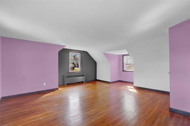 bonus room with hardwood / wood-style floors, vaulted ceiling, radiator, and baseboards