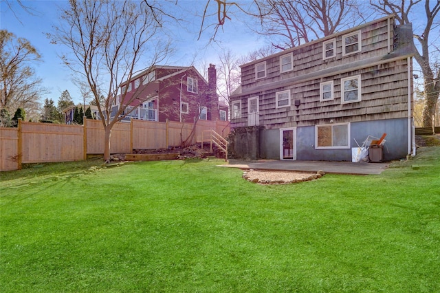 rear view of property featuring a patio area, fence, and a lawn