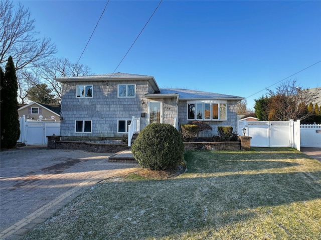 tri-level home featuring fence, a front lawn, and a gate