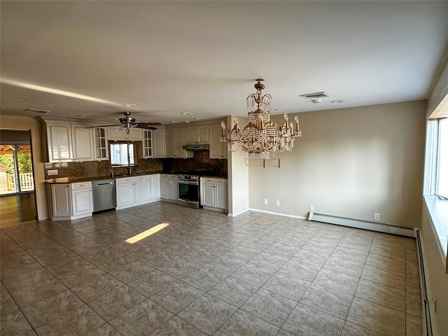 kitchen featuring under cabinet range hood, a baseboard heating unit, dark countertops, stainless steel appliances, and decorative backsplash