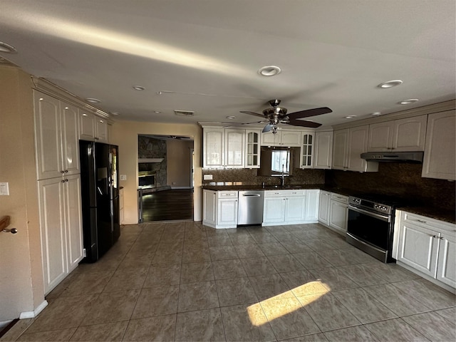 kitchen featuring dark countertops, visible vents, backsplash, under cabinet range hood, and stainless steel appliances