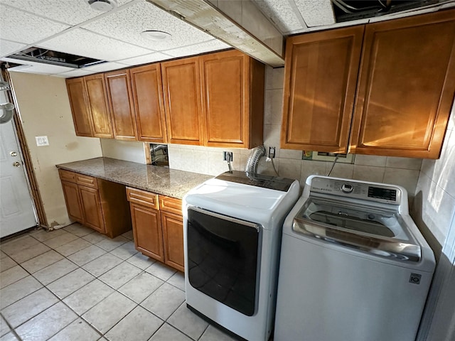 laundry area featuring washer and clothes dryer, light tile patterned floors, and cabinet space