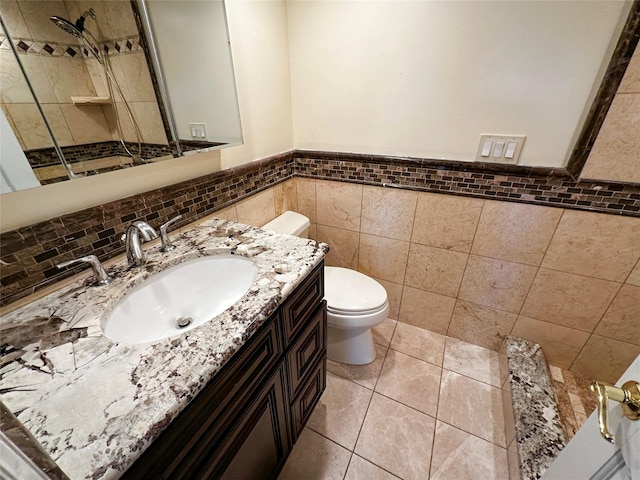 bathroom featuring tile patterned floors, a wainscoted wall, toilet, tile walls, and vanity