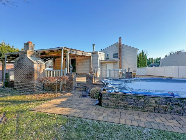 rear view of property featuring a fenced in pool, a patio, and fence