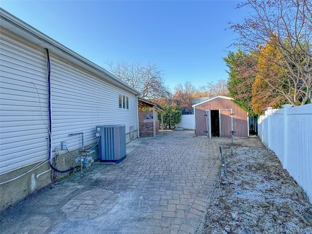 exterior space with an outbuilding, a patio, a fenced backyard, a storage shed, and central AC unit