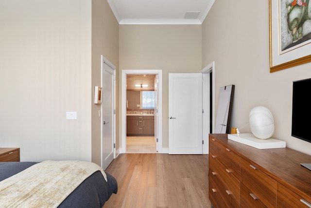 bedroom with visible vents, connected bathroom, light wood-type flooring, and ornamental molding