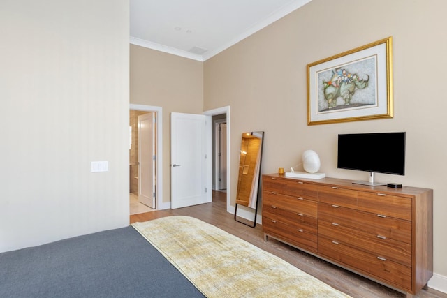 bedroom featuring light wood-type flooring, baseboards, ornamental molding, and a towering ceiling