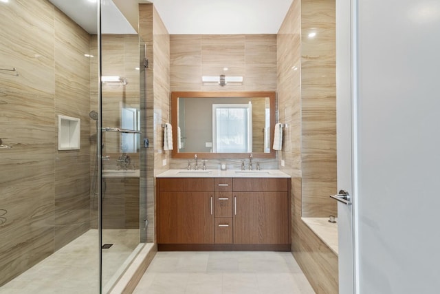 bathroom with double vanity, a shower stall, tile walls, and a sink