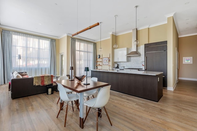 dining area with baseboards, light wood-style floors, and ornamental molding