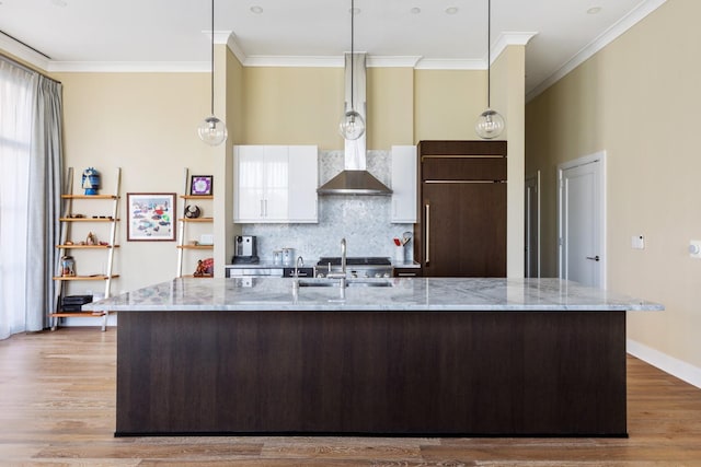 kitchen with white cabinetry, crown molding, light wood finished floors, and a spacious island