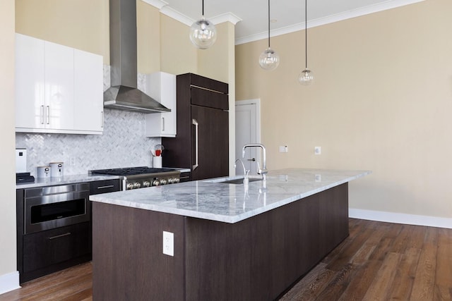 kitchen with dark wood-type flooring, ornamental molding, white cabinets, wall chimney range hood, and decorative backsplash