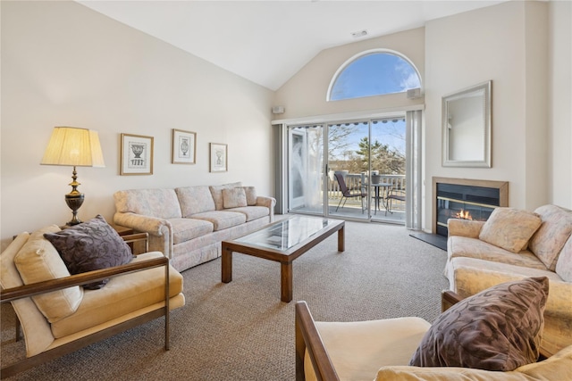 carpeted living room with a glass covered fireplace, visible vents, and high vaulted ceiling