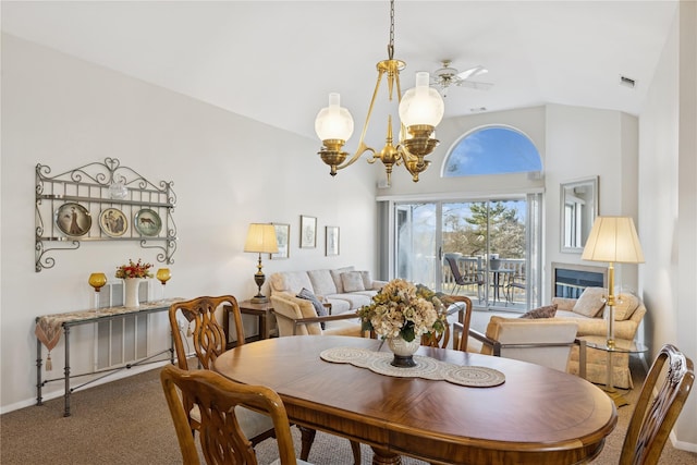 dining room featuring visible vents, ceiling fan with notable chandelier, carpet flooring, baseboards, and vaulted ceiling