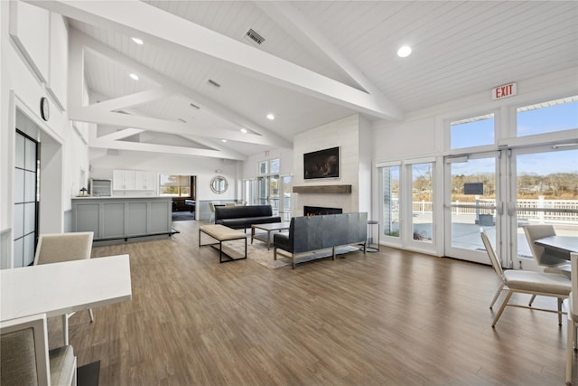 living room featuring beam ceiling, wood finished floors, a fireplace, and visible vents