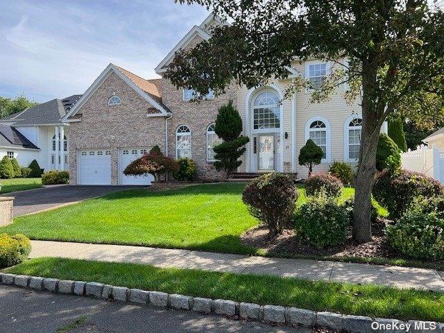 view of front of property with aphalt driveway, an attached garage, and a front lawn