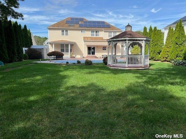 back of house with solar panels, a gazebo, a patio area, and a lawn