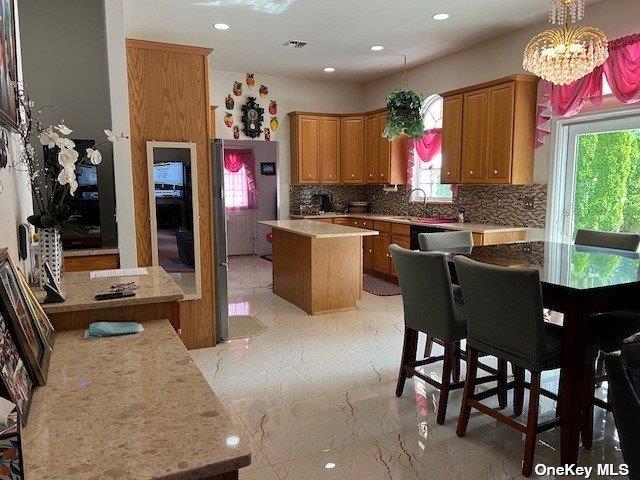 kitchen with a wealth of natural light, visible vents, backsplash, and a center island