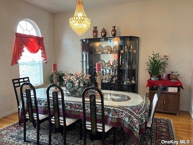 dining room with baseboards, an inviting chandelier, and wood finished floors