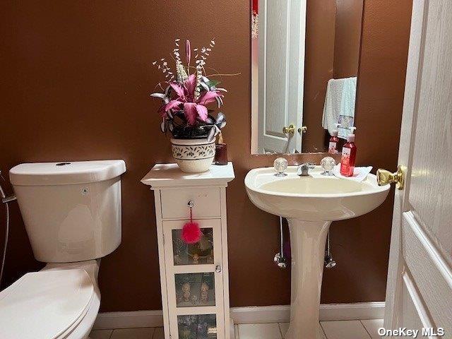 half bathroom featuring baseboards and toilet