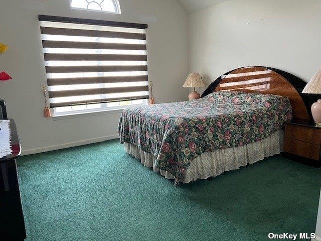 bedroom with baseboards, lofted ceiling, and carpet flooring