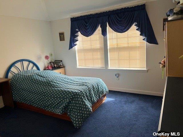 bedroom with vaulted ceiling, baseboards, and carpet floors