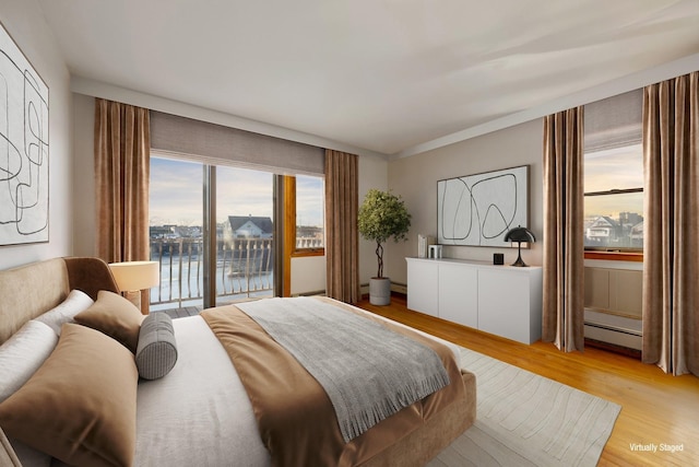 bedroom with light wood-type flooring and a baseboard heating unit