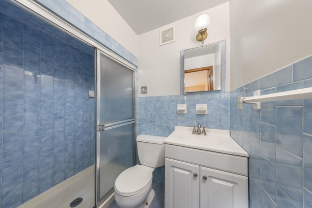 bathroom with vanity, visible vents, a shower stall, tile walls, and toilet