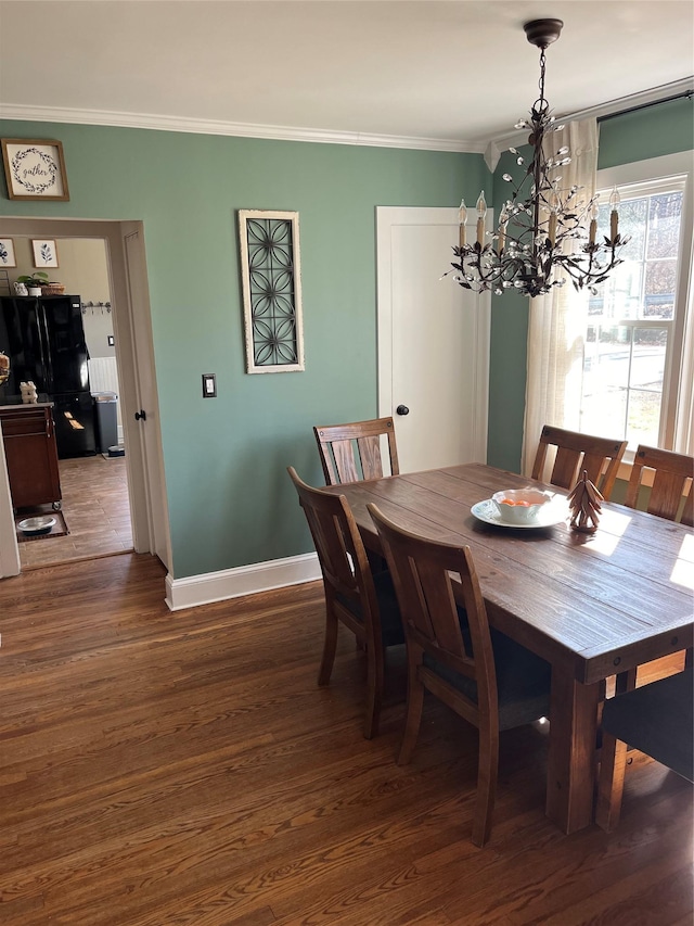 dining area featuring baseboards, wood finished floors, a chandelier, and ornamental molding