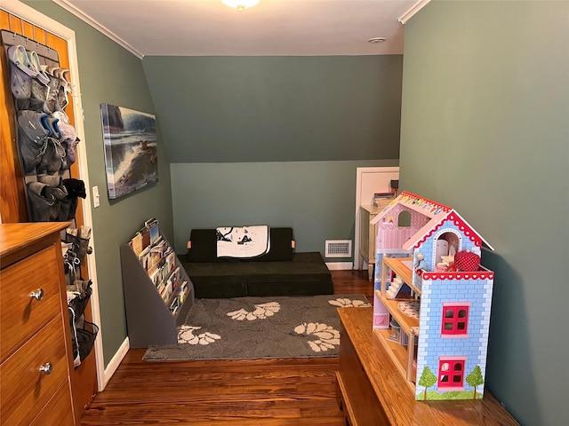 rec room with visible vents, lofted ceiling, wood finished floors, and ornamental molding