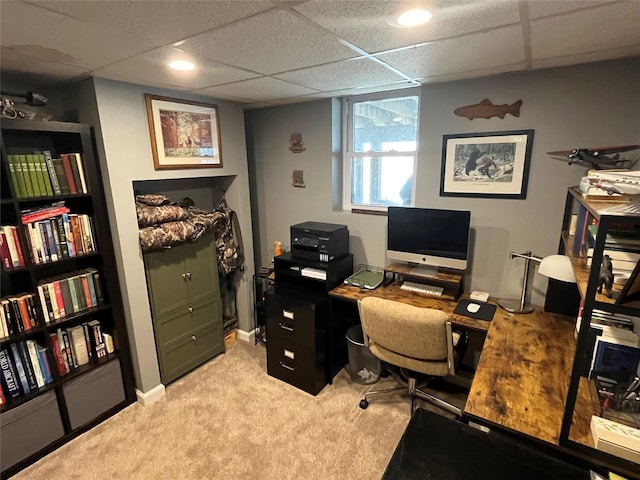 office space featuring a drop ceiling, light carpet, and baseboards