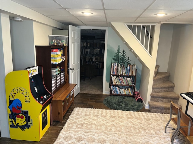 rec room with baseboards, a drop ceiling, and wood tiled floor