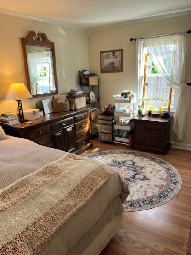 bedroom with crown molding and wood finished floors