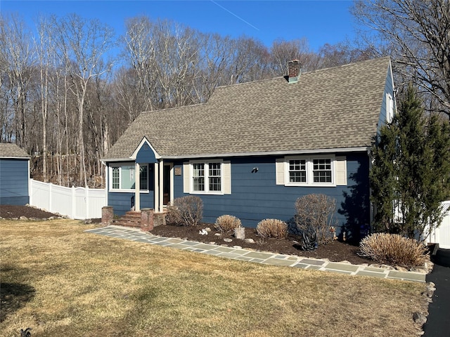 view of front of property with a front lawn, fence, a chimney, and a shingled roof