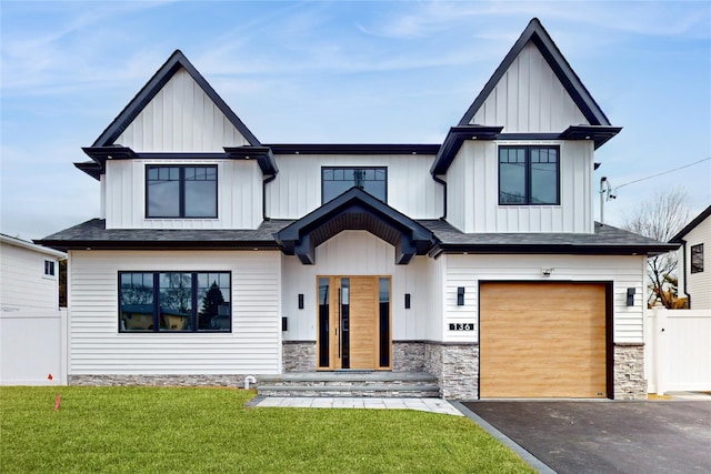 modern farmhouse with fence, driveway, a front lawn, a garage, and board and batten siding