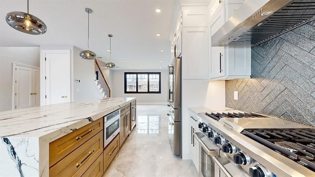 kitchen featuring backsplash, pendant lighting, range hood, appliances with stainless steel finishes, and white cabinetry