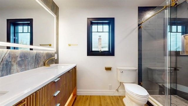 bathroom featuring toilet, wood finished floors, a stall shower, and a wealth of natural light