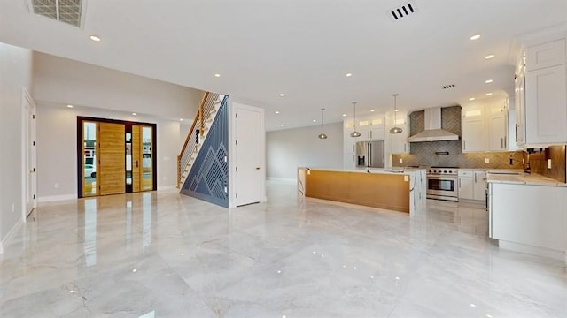 kitchen featuring marble finish floor, a sink, open floor plan, appliances with stainless steel finishes, and wall chimney exhaust hood