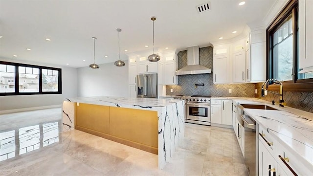 kitchen with visible vents, a sink, a kitchen island, stainless steel appliances, and wall chimney exhaust hood