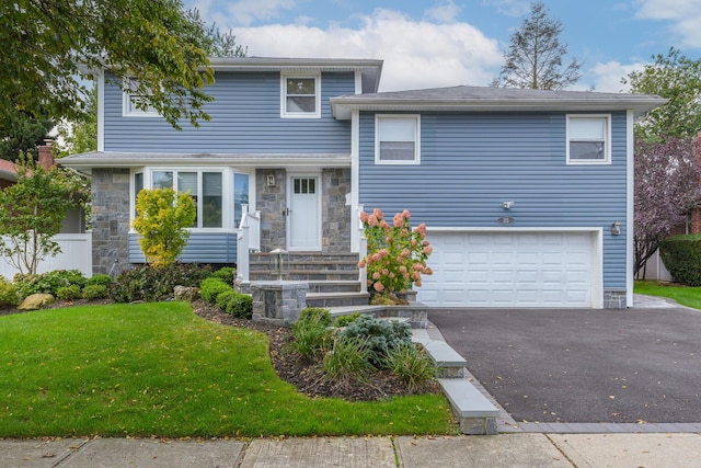 tri-level home featuring a front lawn, an attached garage, stone siding, and driveway