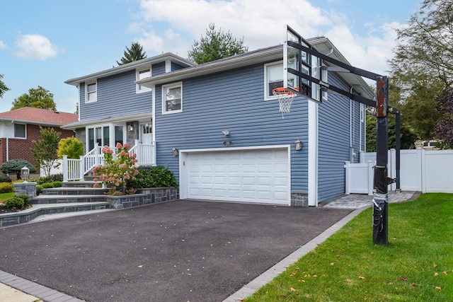 tri-level home featuring aphalt driveway, an attached garage, fence, and a front lawn