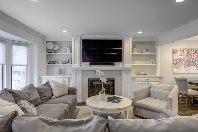 living room with light wood-type flooring, built in shelves, ornamental molding, recessed lighting, and a premium fireplace