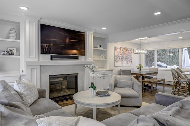 living room with built in shelves, ornamental molding, wood finished floors, a high end fireplace, and recessed lighting